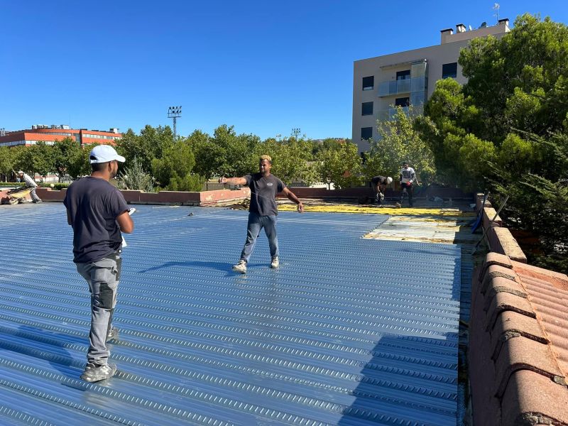 Dos profesionales con camiseta negra encima de tejado plano