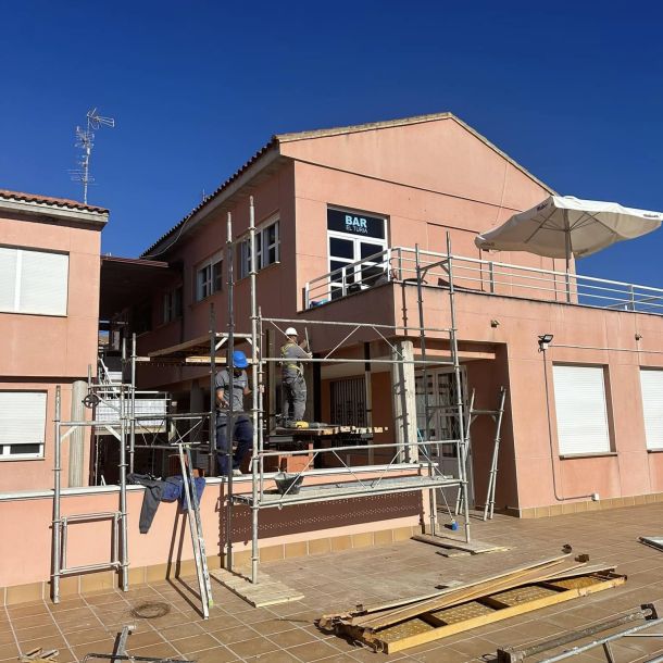 Edificio cubierto por estructura metálica y profesionales trabajando en rehabilitación 