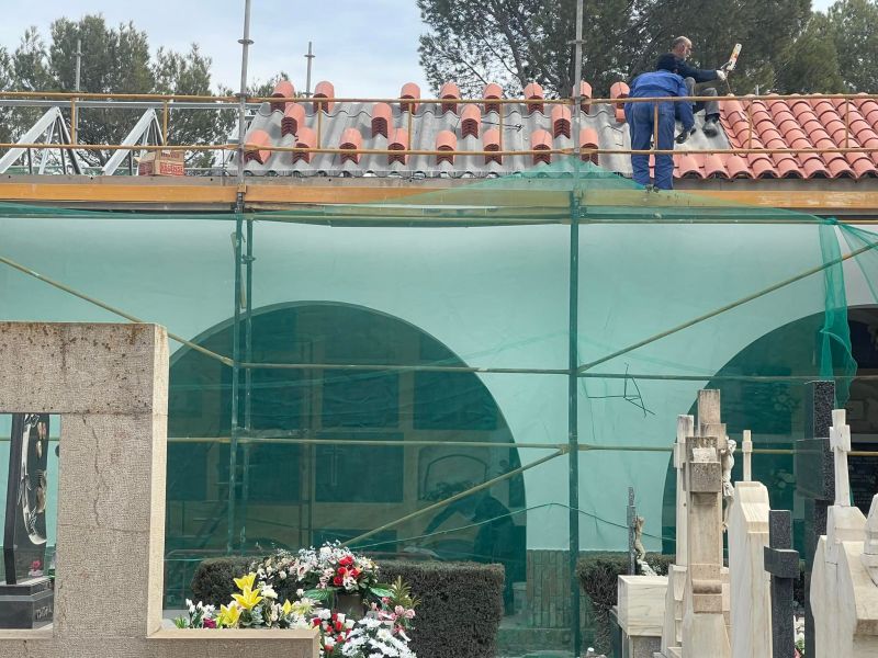 Imagen de obrero arreglando el techo del cementerio de Teruel subido a una estructura metálica 