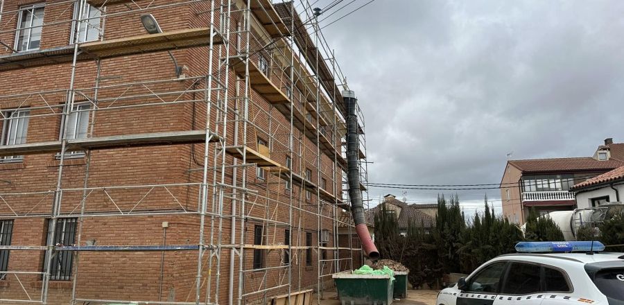 Fachada cubierta por estructura metálica y contenedor de escombros 
