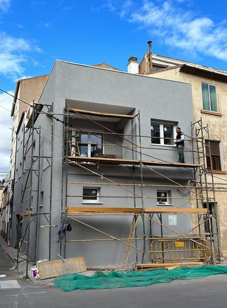 Fachada de edificio gris oscuro con plataforma metálica protegiendo 